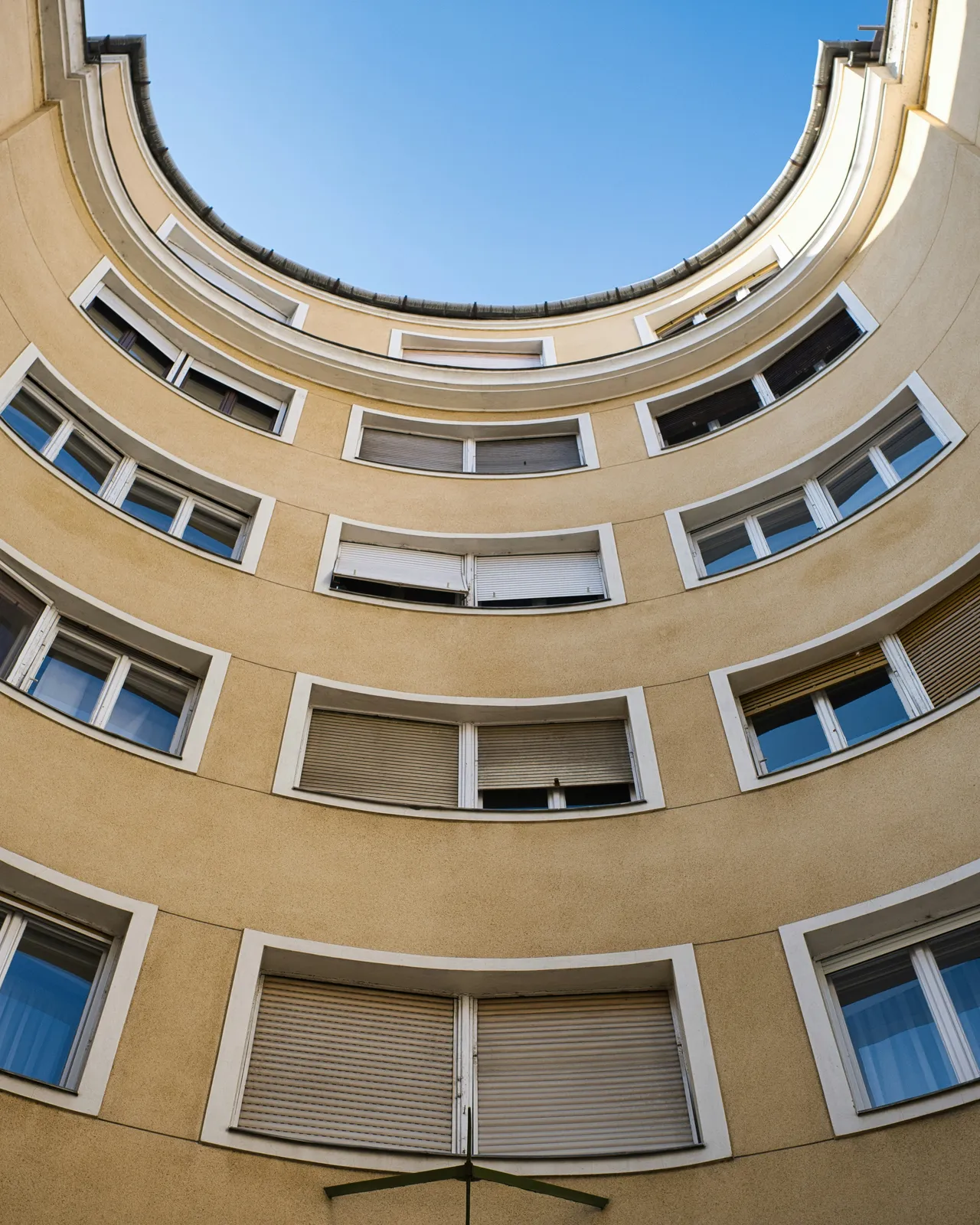 Gebogene Fassade eines Mehrfamilienhauses mit vielen Wohnungsfenstern, von unten aufgenommen