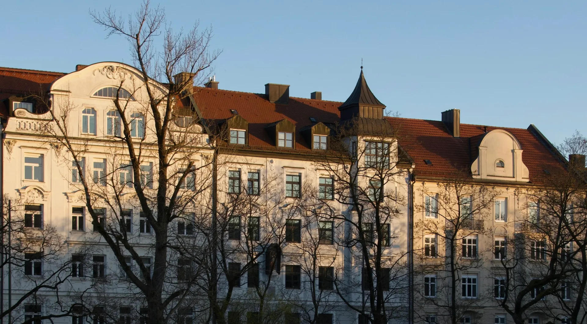 Zeile verputzter Altbauten mit Ziegeldächern im Abendlicht