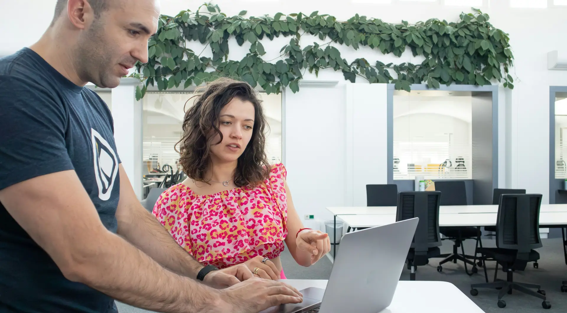 Zwei Menschen sitzen in einem hellen Büro an einem Laptop und besprechen eine Seite